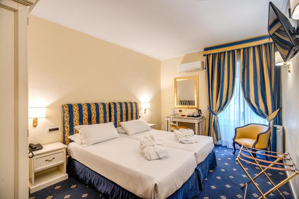a hotel room with two beds and a chair at Hotel Napoleon in Rome