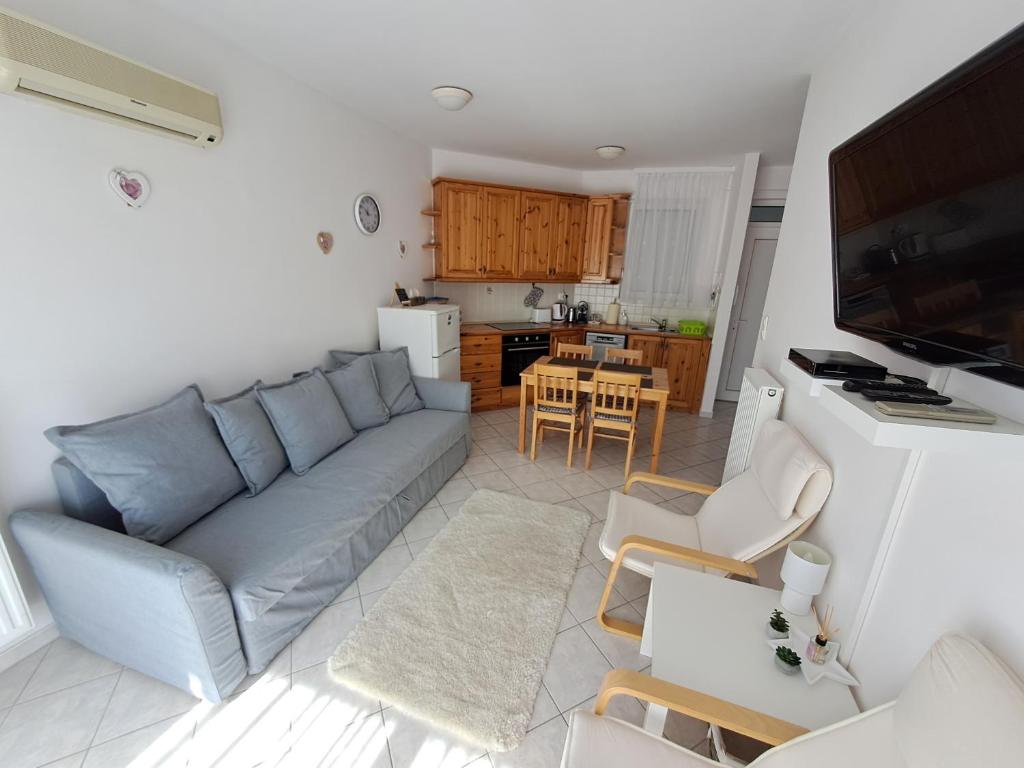 a living room with a couch and a kitchen at Plázs Apartman Balatonlelle in Balatonlelle