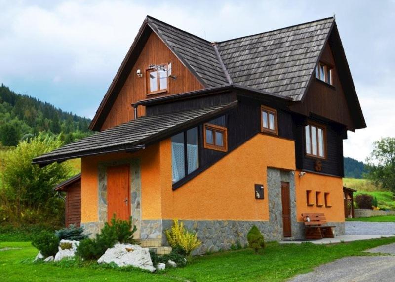 a house with a black roof and orange at Chata na Plantáži in Habovka