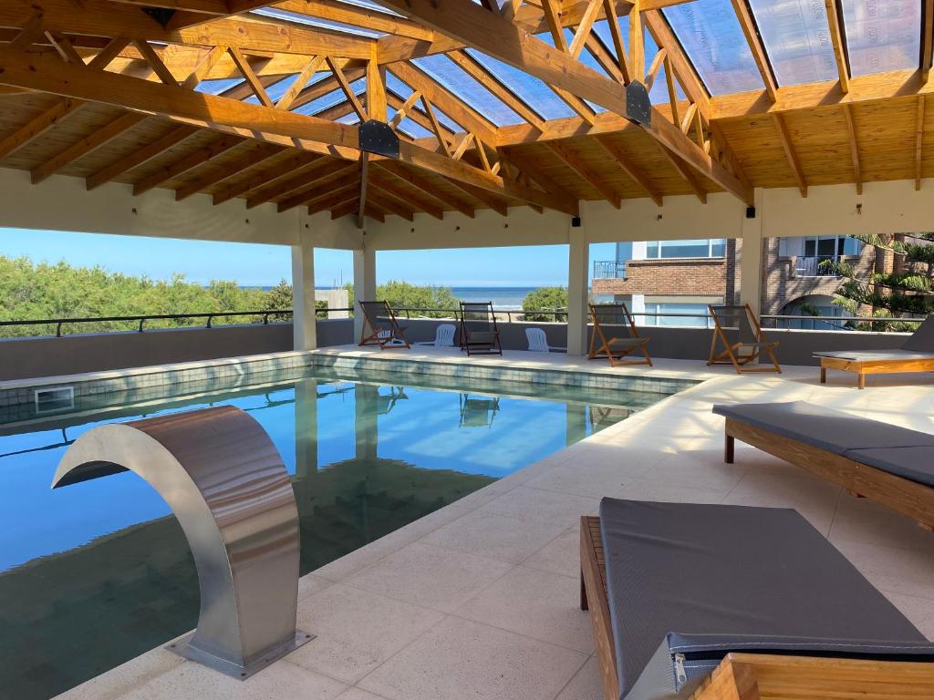 a swimming pool with chairs and a roof at Costanera Mar Hotel & Suites in San Clemente del Tuyú