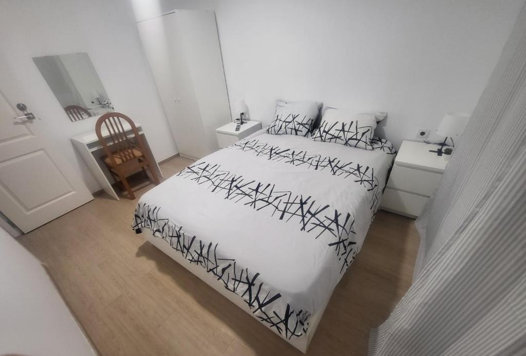 Habitaciones con baño compartido en bonito Apartamento en Badalona في بادالونا: غرفة نوم بسرير بملاءات سوداء وبيضاء