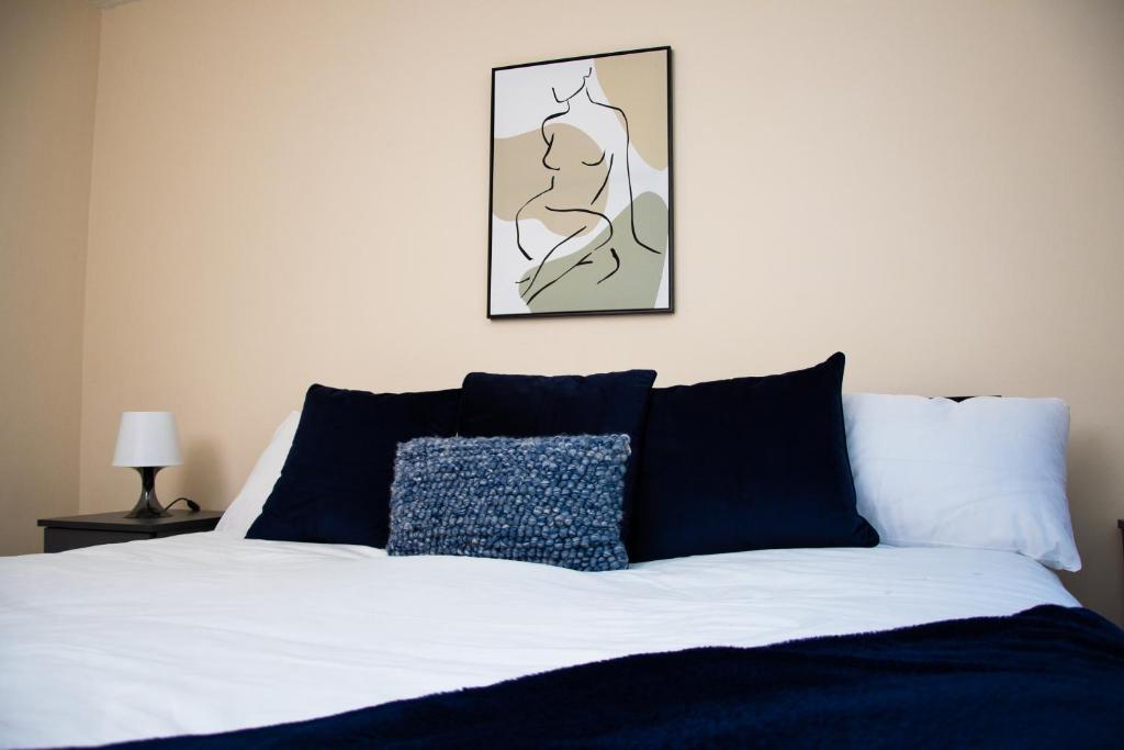 1 cama con almohadas azules y una foto en la pared en XB Property - Comfy house perfect for families contractors relocators, en West Bromwich