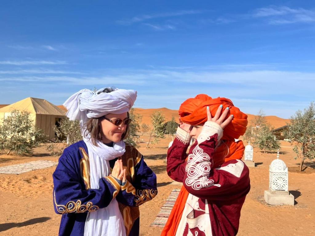 two women dressed in costumes standing in the desert at Roses desert camp in Merzouga