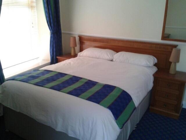 uma cama com um cobertor listrado azul e verde em The Grafton Rooms em Northampton