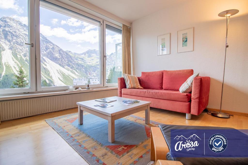 a living room with a red couch and a table at Viktoria B42 by Arosa Holiday in Arosa