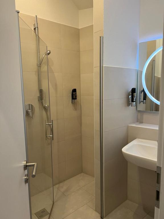 a shower with a glass door next to a sink at Slamba Hostel in Augsburg