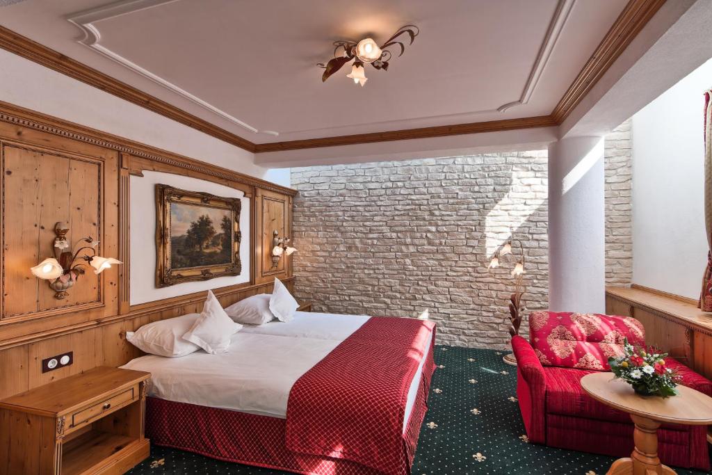 a hotel room with a bed and a red chair at Mercure Sighisoara Binderbubi Hotel & Spa in Sighişoara