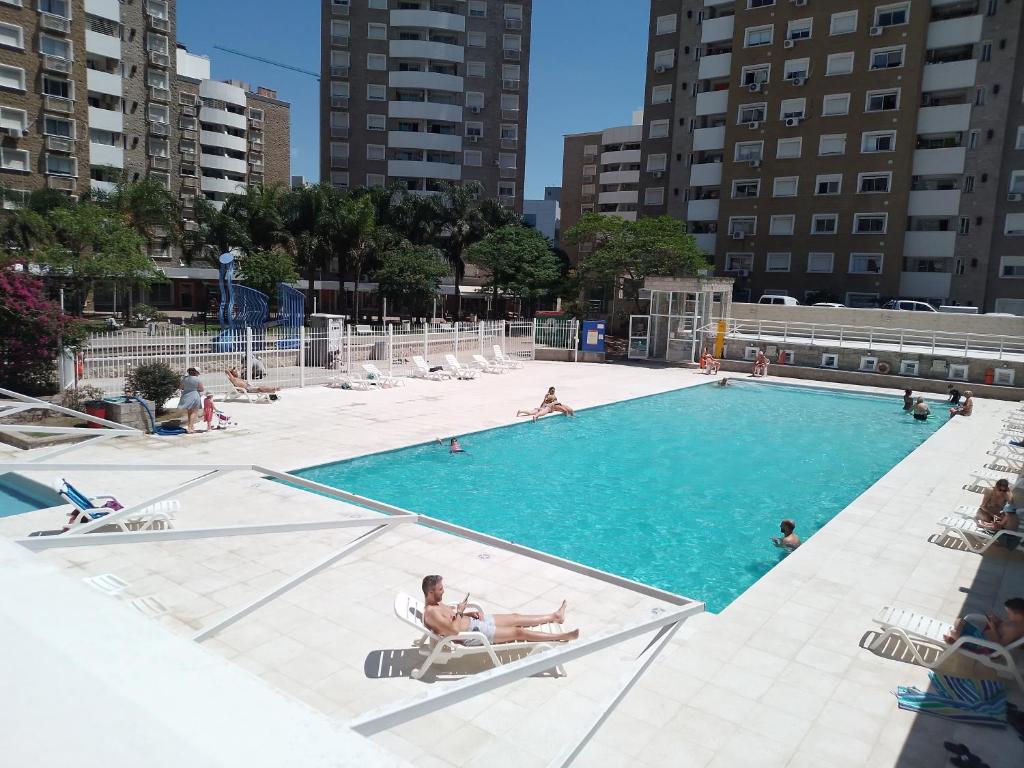 a large swimming pool with people sitting in chairs in it at Villasol Temporario in Córdoba