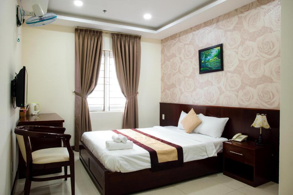 een slaapkamer met een bed, een bureau en een stoel bij LUXURY HOTEL HẬU GIANG in Ho Chi Minh-stad