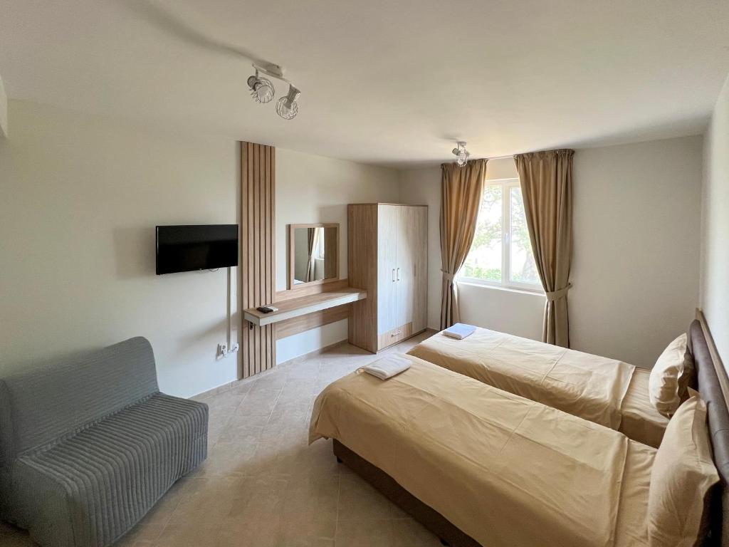 1 dormitorio con 1 cama, 1 silla y TV en Guest Houses Kapatovo / Къщи за гости КАПАТОВО, 