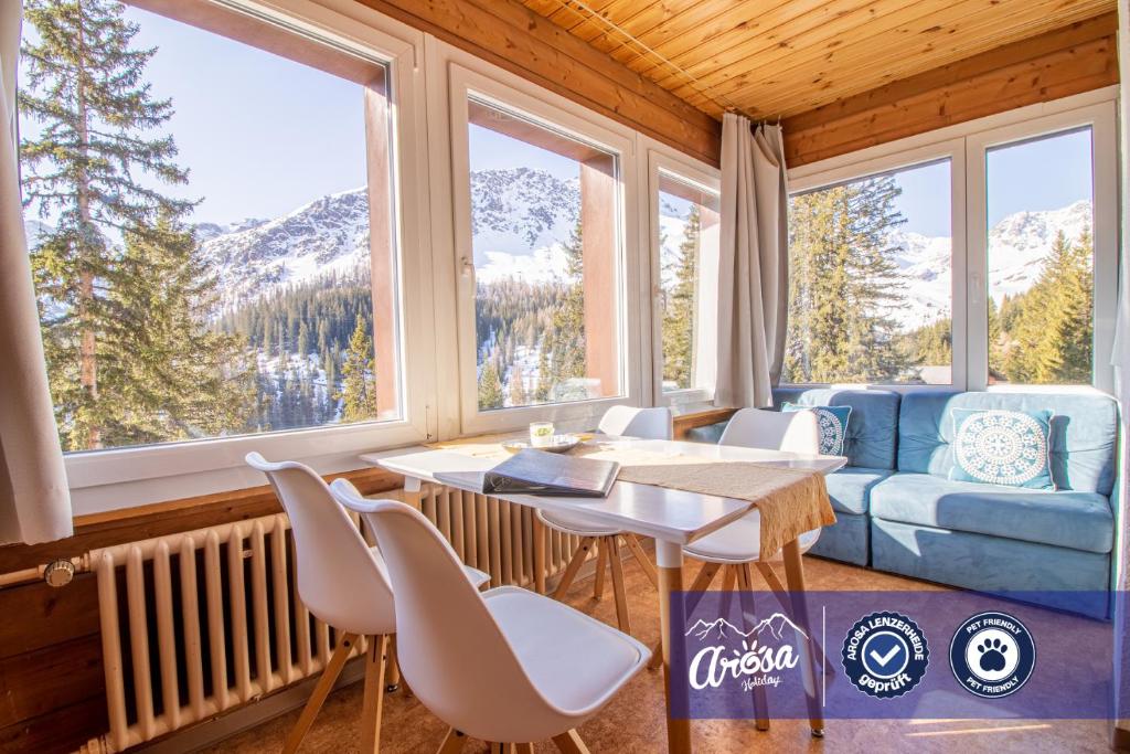 a living room with a table and chairs and windows at Miraflor Sonja by Arosa Holiday in Arosa