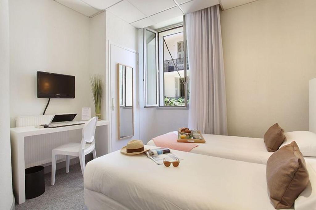 a hotel room with two beds and a desk at Hôtel P.L.M. in Cannes
