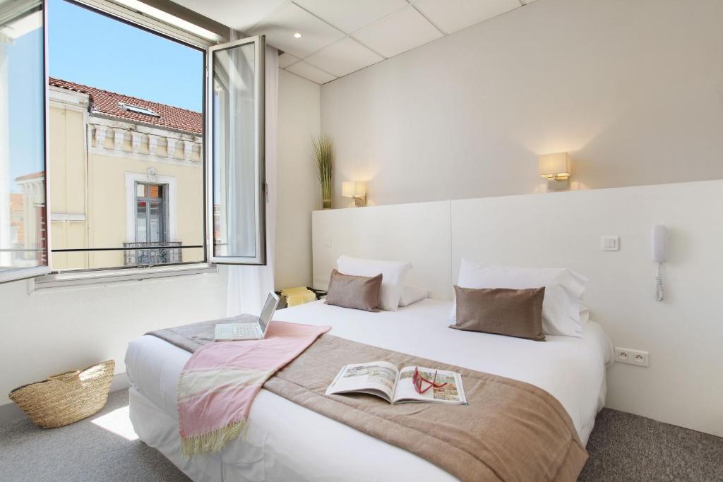 a bedroom with a large bed with a book on it at Hôtel P.L.M. in Cannes