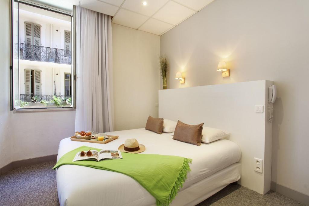 a hotel room with a bed with hats and books on it at Hôtel P.L.M. in Cannes