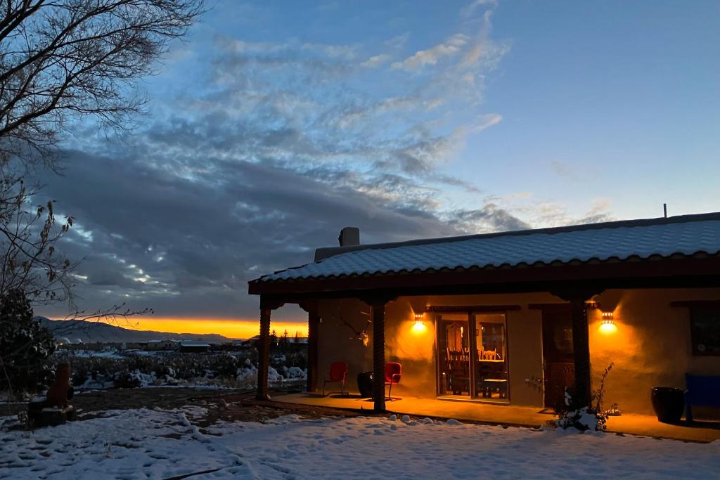 una casa en la nieve con la puesta de sol en el fondo en Valerio Dreams, en El Prado