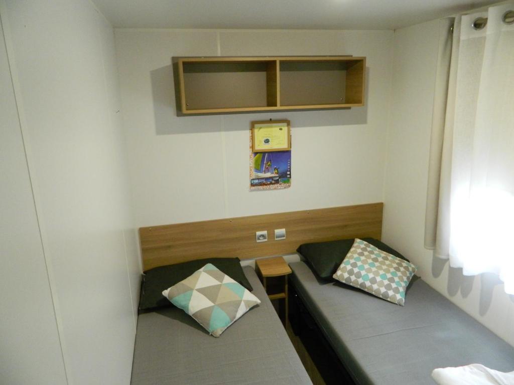 a room with two beds in a small room at Charmant mobil home 331 camping 4* Siblu La Réserve in Gastes