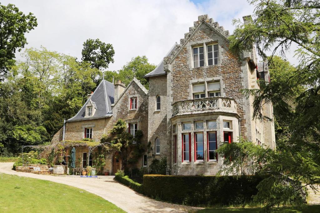 une ancienne maison en pierre avec des portes rouges et une allée. dans l'établissement Manoir de Truhelin, à 2 pas du Golfe du Morbihan, à Arradon