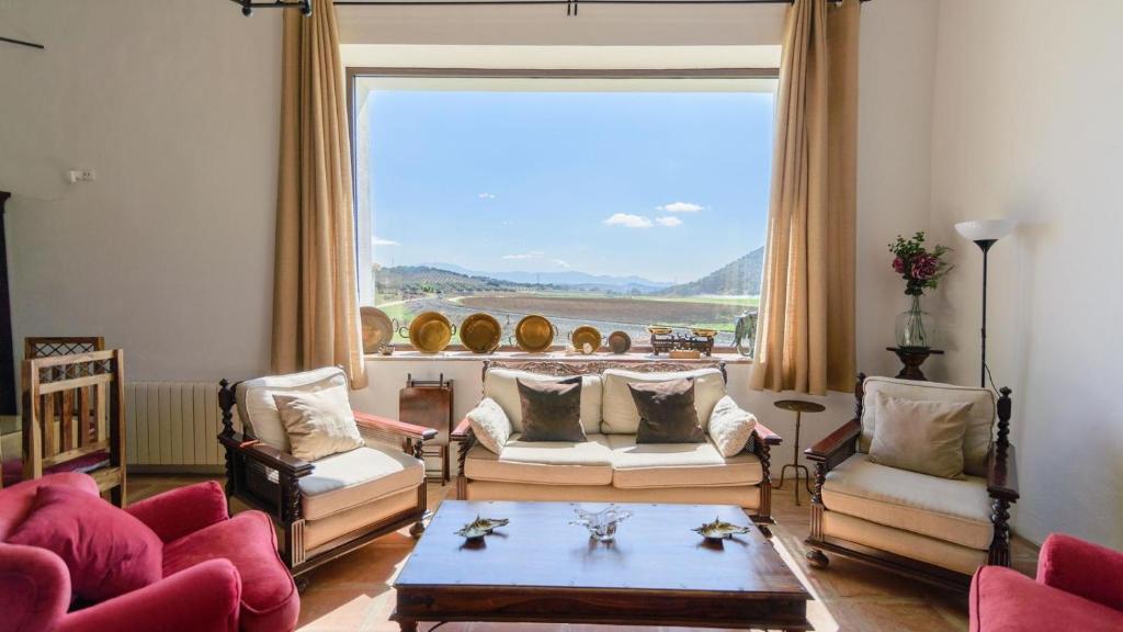 a living room with chairs and a table and a large window at El Molino de María Archidona by Ruralidays in Archidona