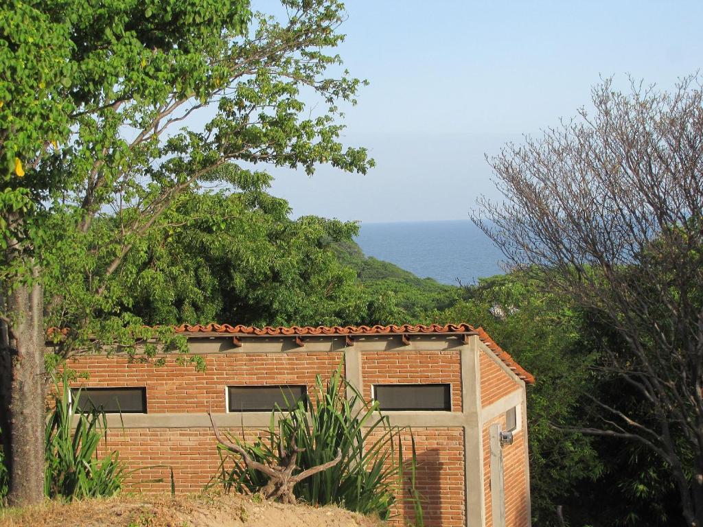 ein Backsteingebäude mit dem Ozean im Hintergrund in der Unterkunft Centro Sati Bungalos in Cuatunalco