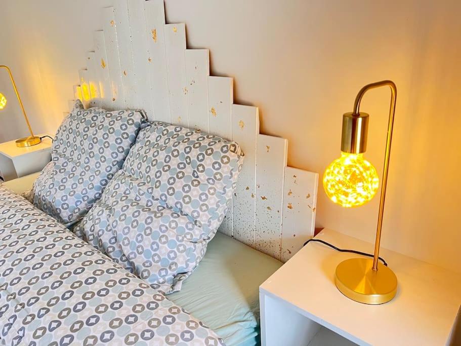 Una cama con almohadas azules y una lámpara en una mesa. en Studio à 20 min des cures thermales de La Roche Posay - Casino, en Archigny