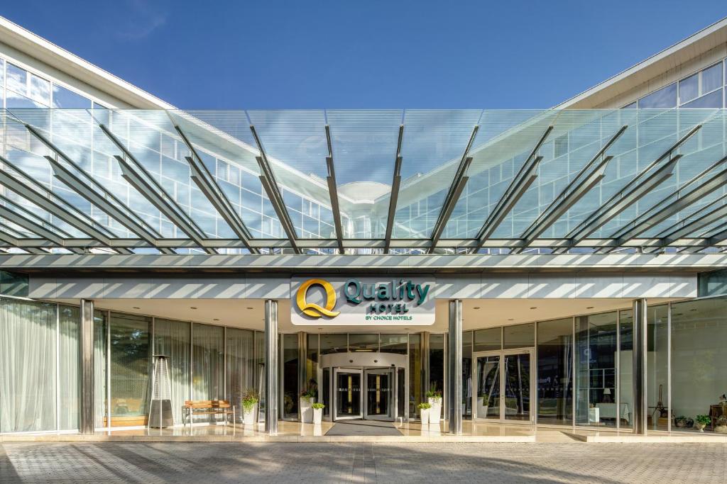 a large glass building with a q authority sign on it at Quality Hotel Brno Exhibition Centre in Brno