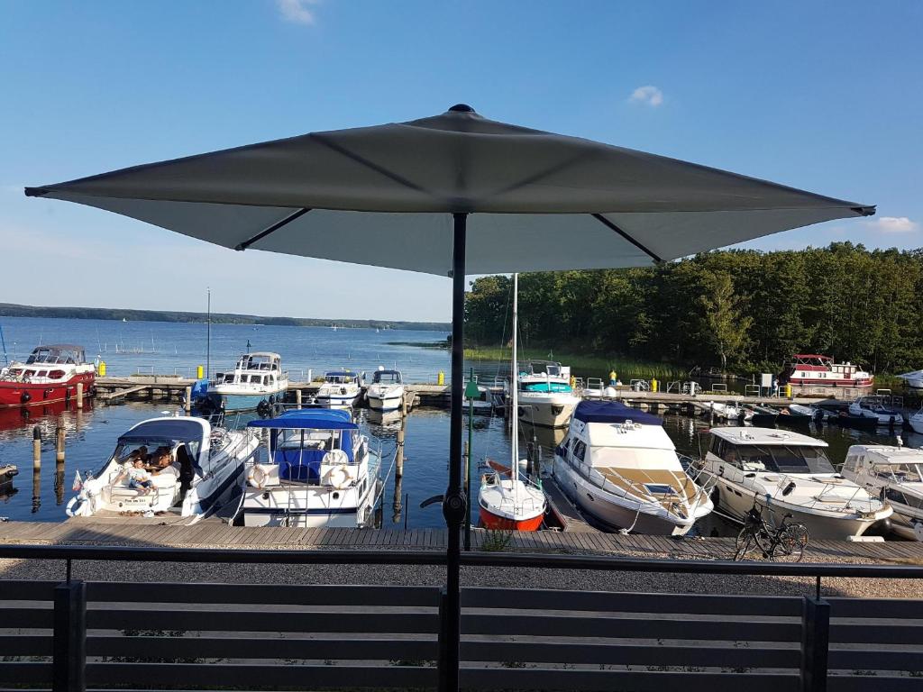 un grand parapluie en face d'un port de plaisance avec des bateaux dans l'établissement Maisonette Jocki P6 A9, à Plau am See