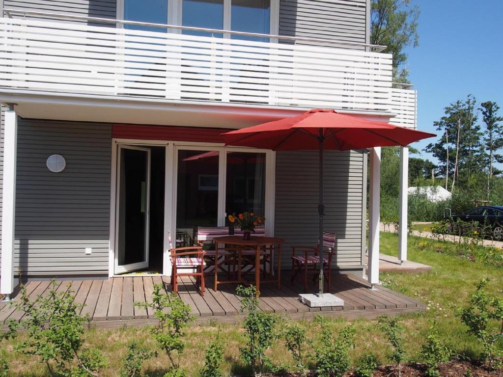 eine Terrasse mit einem Tisch und einem roten Regenschirm in der Unterkunft Hafenperle P5A5 Nr37 in Plau am See