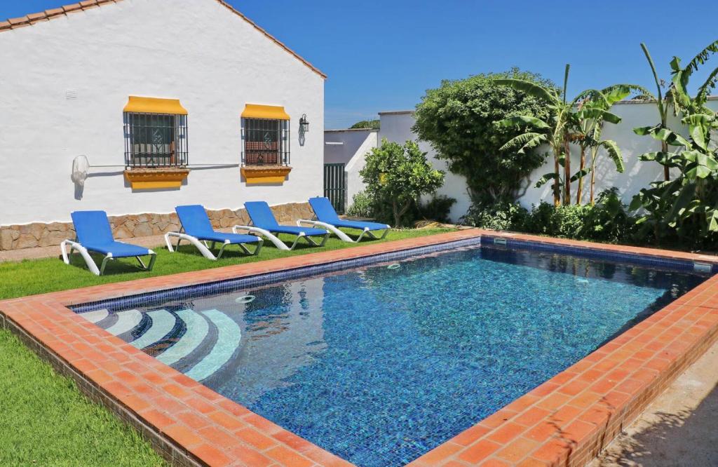 a swimming pool with blue chairs next to a house at Chalet Dehesa Villa in Conil de la Frontera