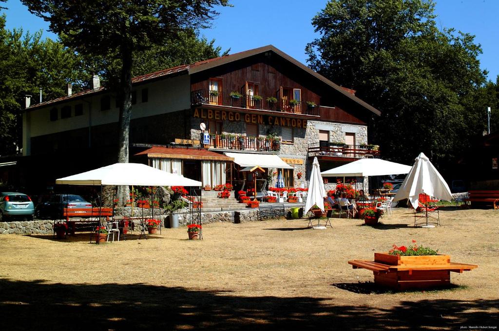 un bâtiment avec des tables et des parasols devant lui dans l'établissement Albergo Generale Cantore - Monte Amiata, à Abbadia San Salvatore