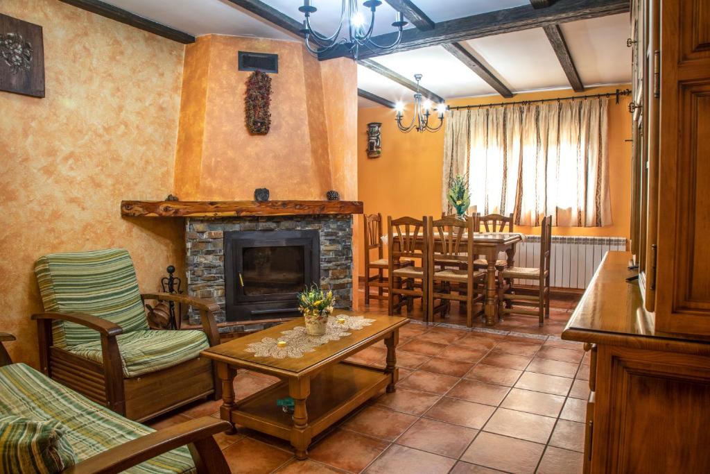 sala de estar con chimenea, mesa y sillas en Apartamentos Cruz Mar en Poveda de la Sierra