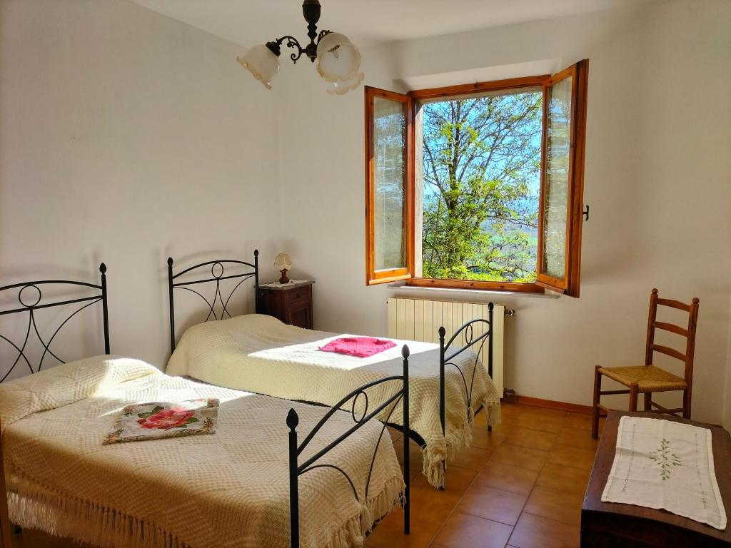 2 Betten in einem Zimmer mit einem Fenster und einem Tisch in der Unterkunft L'oca Nera in Chiusi
