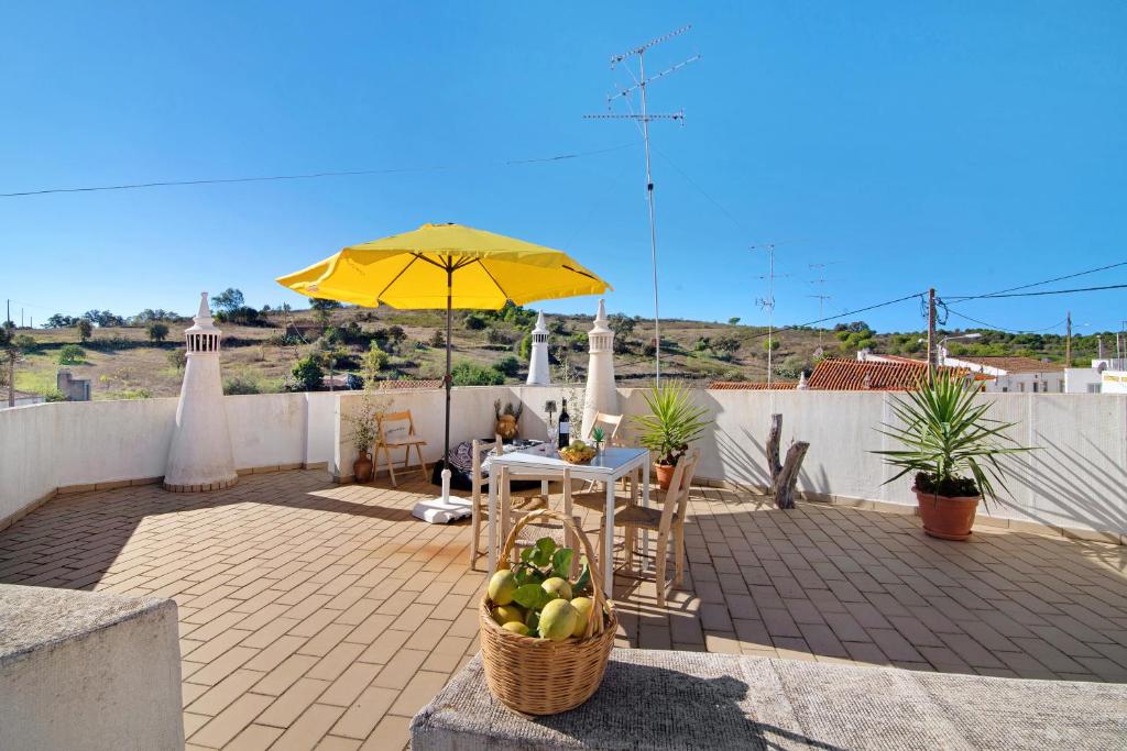 a patio with a table and a yellow umbrella at Casa do Lavrador Furnazinhas in Odeleite