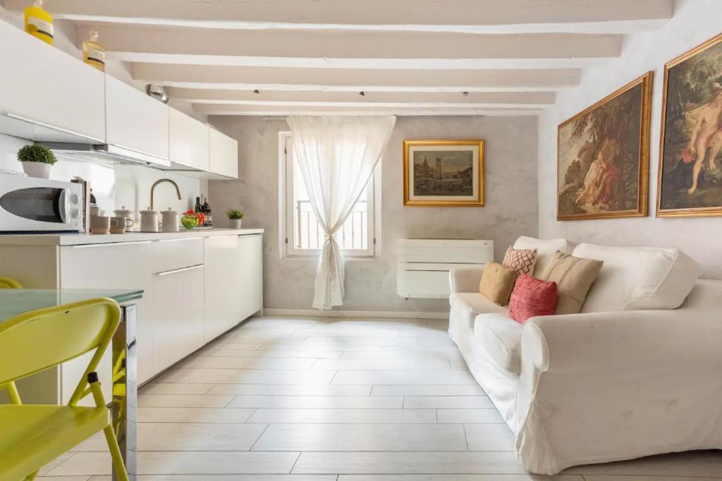 Il comprend un salon avec un canapé blanc et une cuisine. dans l'établissement MMeSuite Arena di Verona by Maisonme Collection, à Vérone