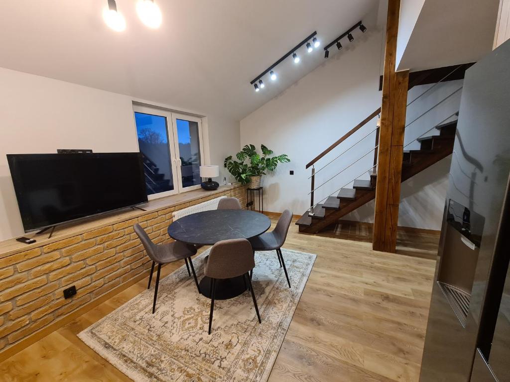 a living room with a table and chairs and a tv at Apartamenty Osmolice w Stawach in Dęblin