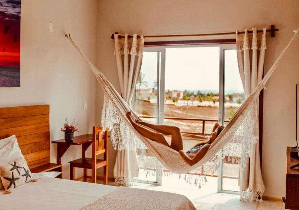 a hammock in a bedroom with a large window at Pousada Naná in Prea