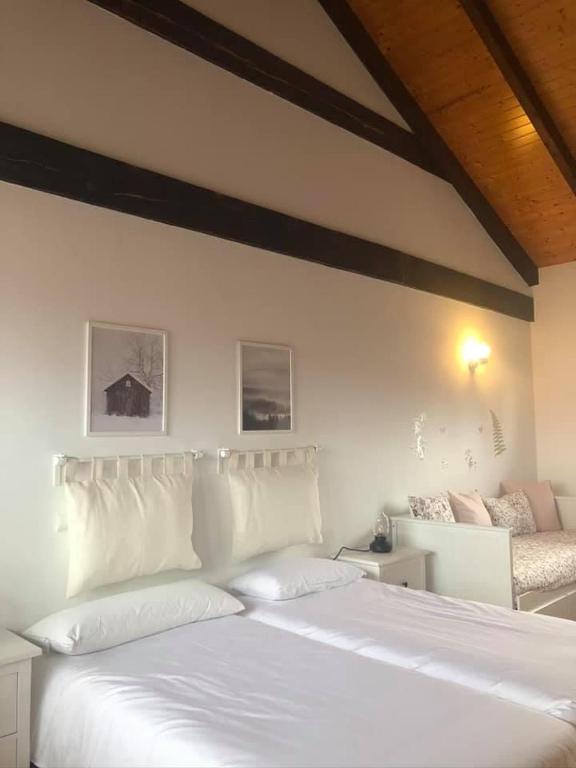 a white bed with white pillows in a bedroom at Las Raucas in Colombres