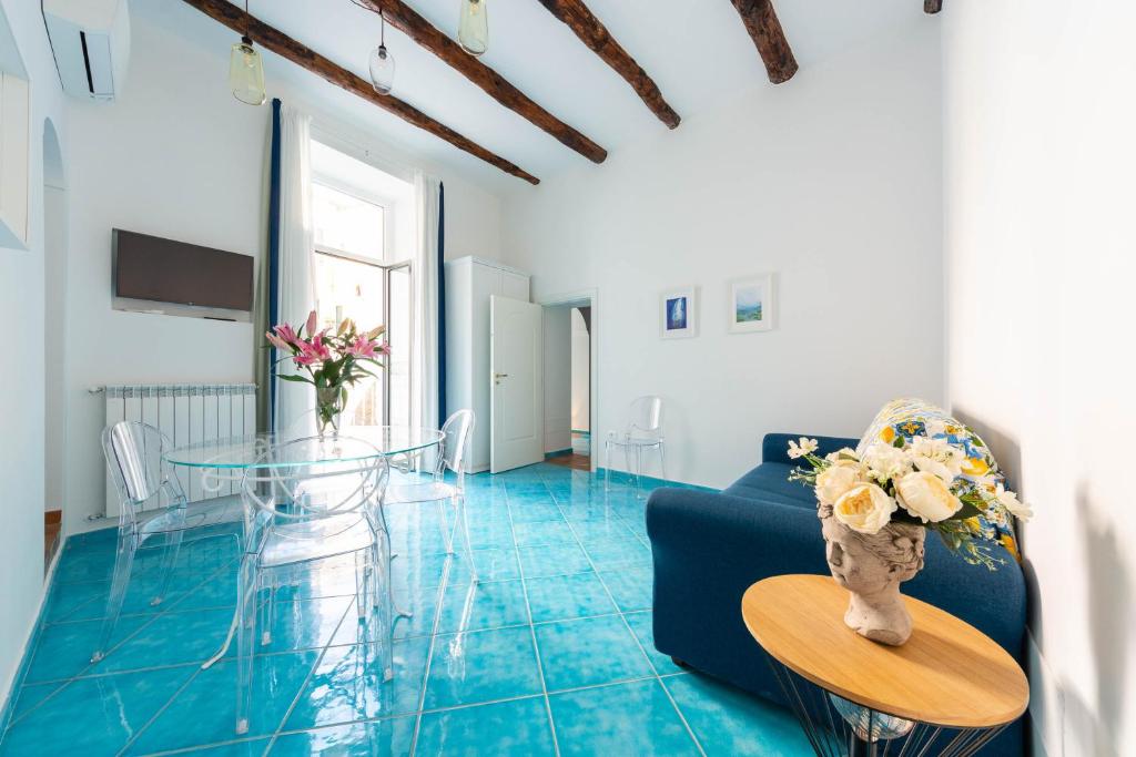 un salon avec une table en verre et du carrelage bleu dans l'établissement Amalfi Ammorè, à Amalfi