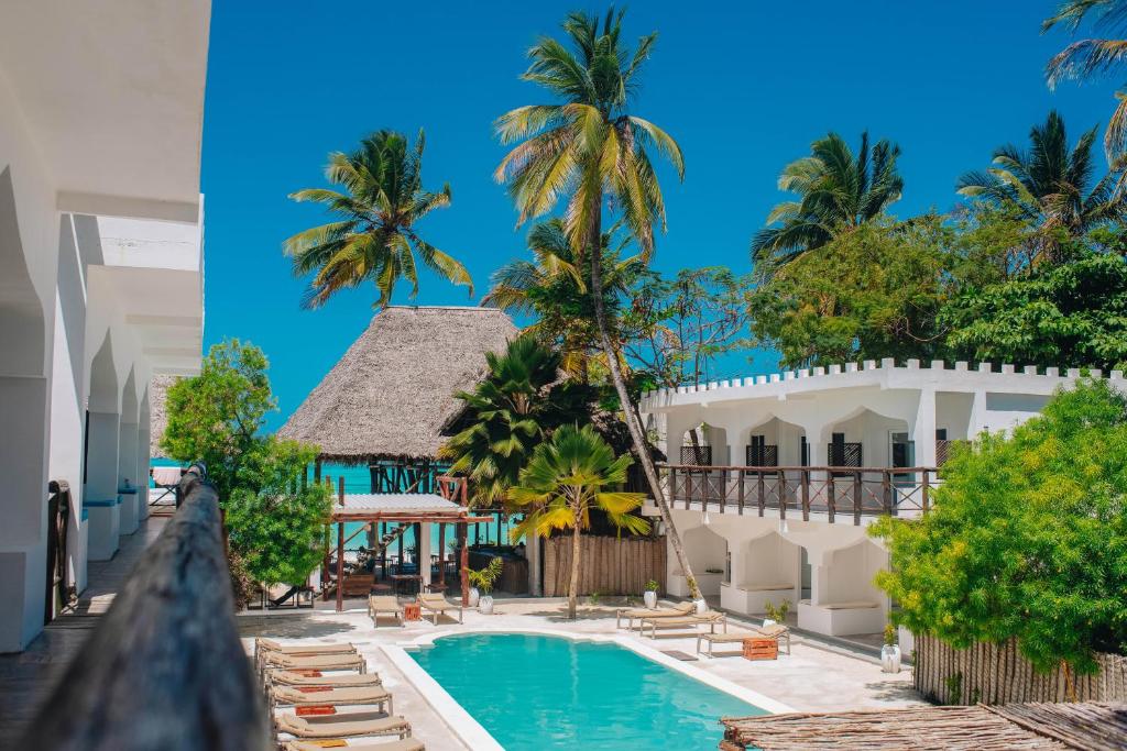 a view of a resort with a swimming pool and palm trees at Dhow Resort in Jambiani