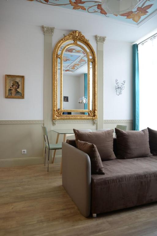 uma sala de estar com um sofá e um espelho em Le Stanislas, un style! em Nancy