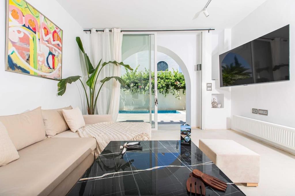 a living room with a white couch and a glass table at Duplex avec piscine Détente et élégance in Gammarth