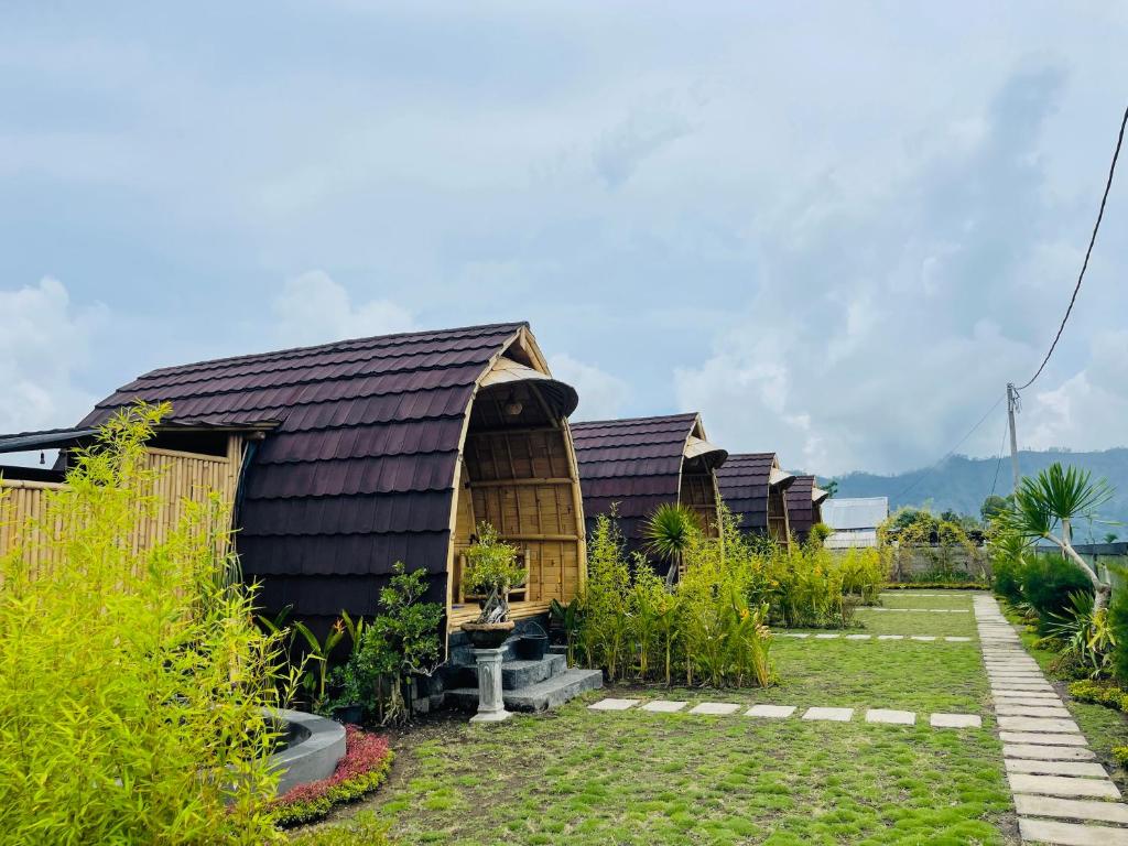 a row of wooden huts in a garden at Tegal Bamboo cottages & private hot spring in Baturaja