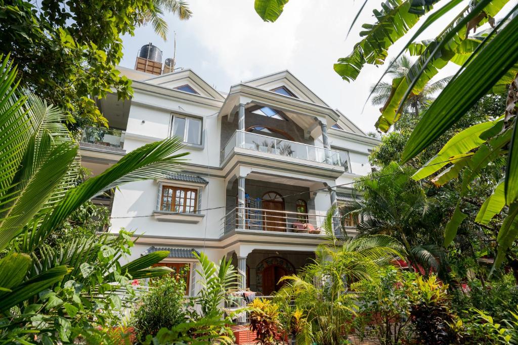 a large white house surrounded by trees at Palolem Apartments in Palolem