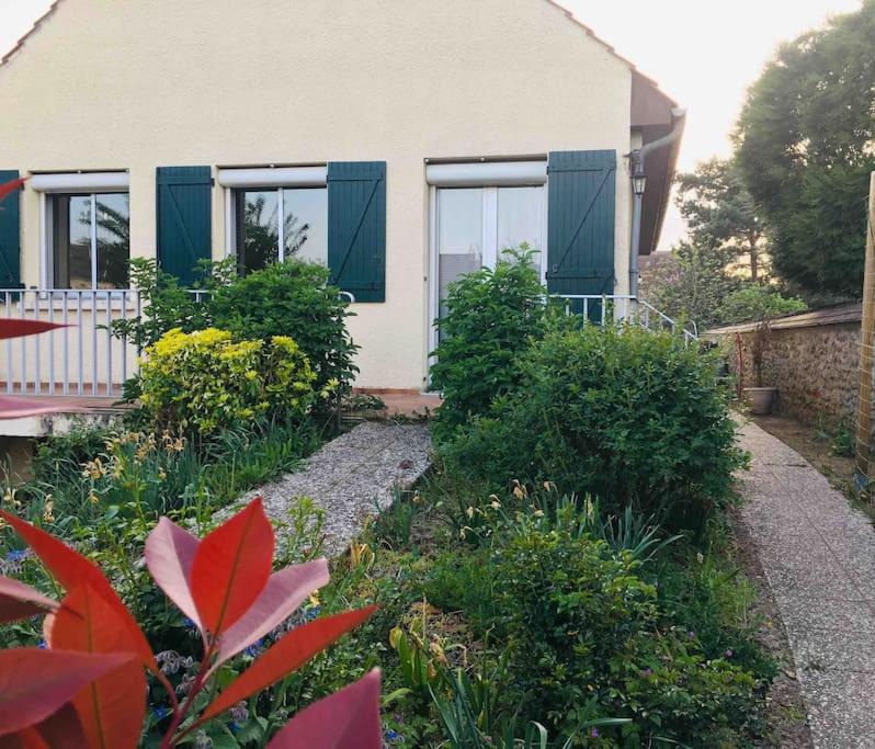 a house with green shuttered windows and a garden at Appartement coquet dans maison individuelle in Lisses