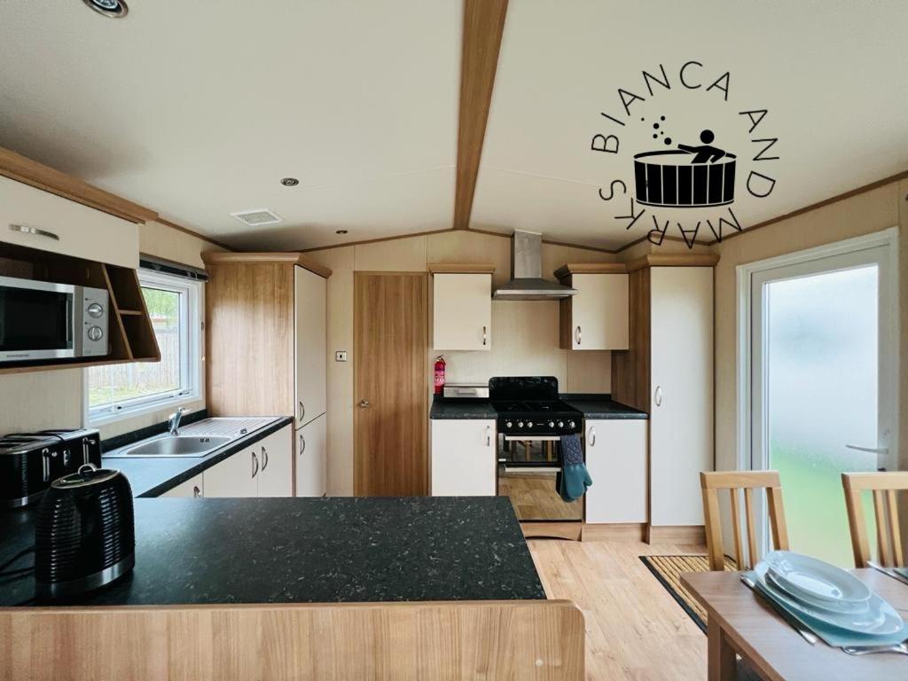 uma cozinha com um balcão preto num quarto em Bianca and marks 8 berth Caravan with Hot tub em Tattershall