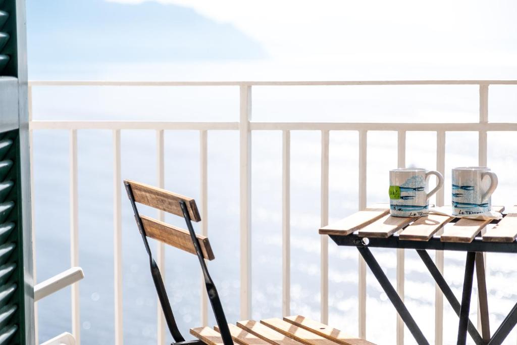 a table with two cups and a chair on a balcony at Hotel Le Terrazze in Conca dei Marini