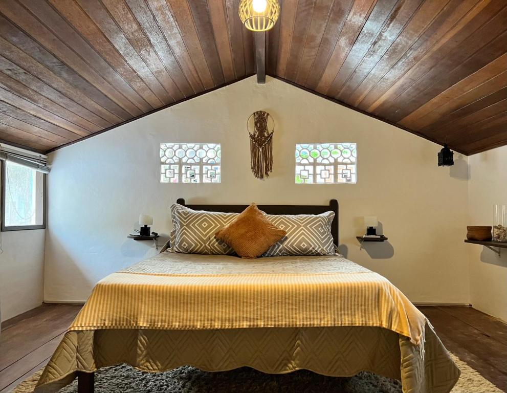 a bedroom with a large bed with a wooden ceiling at Coco Suites in Abraão