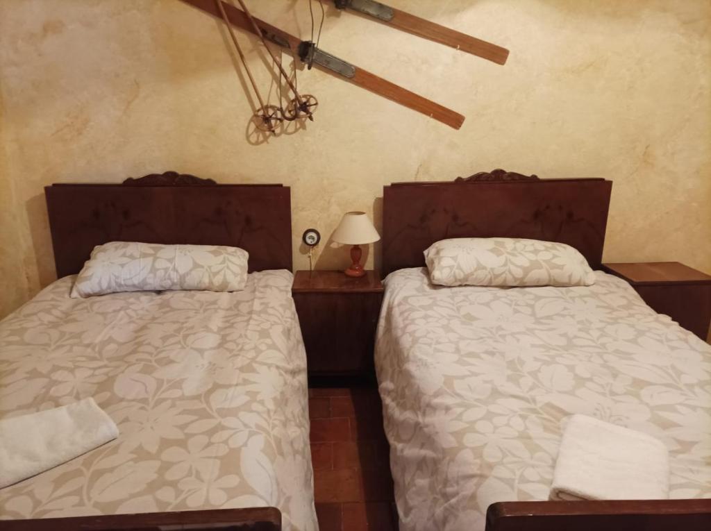 a bedroom with two beds and a table with a lamp at La Casa Amarilla in Rubielos de Mora