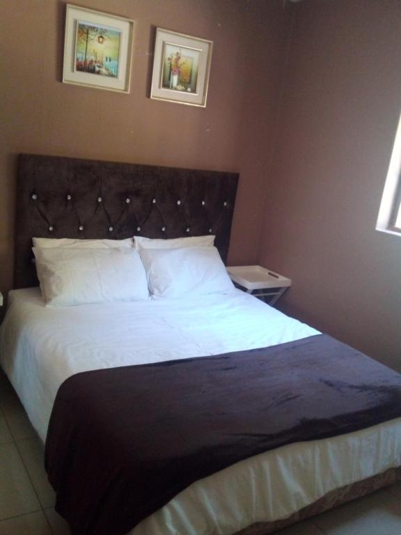 una camera da letto con un grande letto con lenzuola bianche di The Court House- Ramsgate KZN a Ramsgate