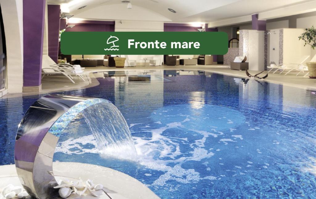 uma piscina interior com uma cascata no átrio do hotel em Yes Hotel Touring & SPA em Rimini