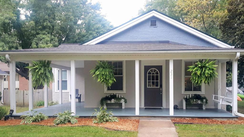 a white house with a porch with plants on it at Cozy cottage near downtown Prescott in Prescott